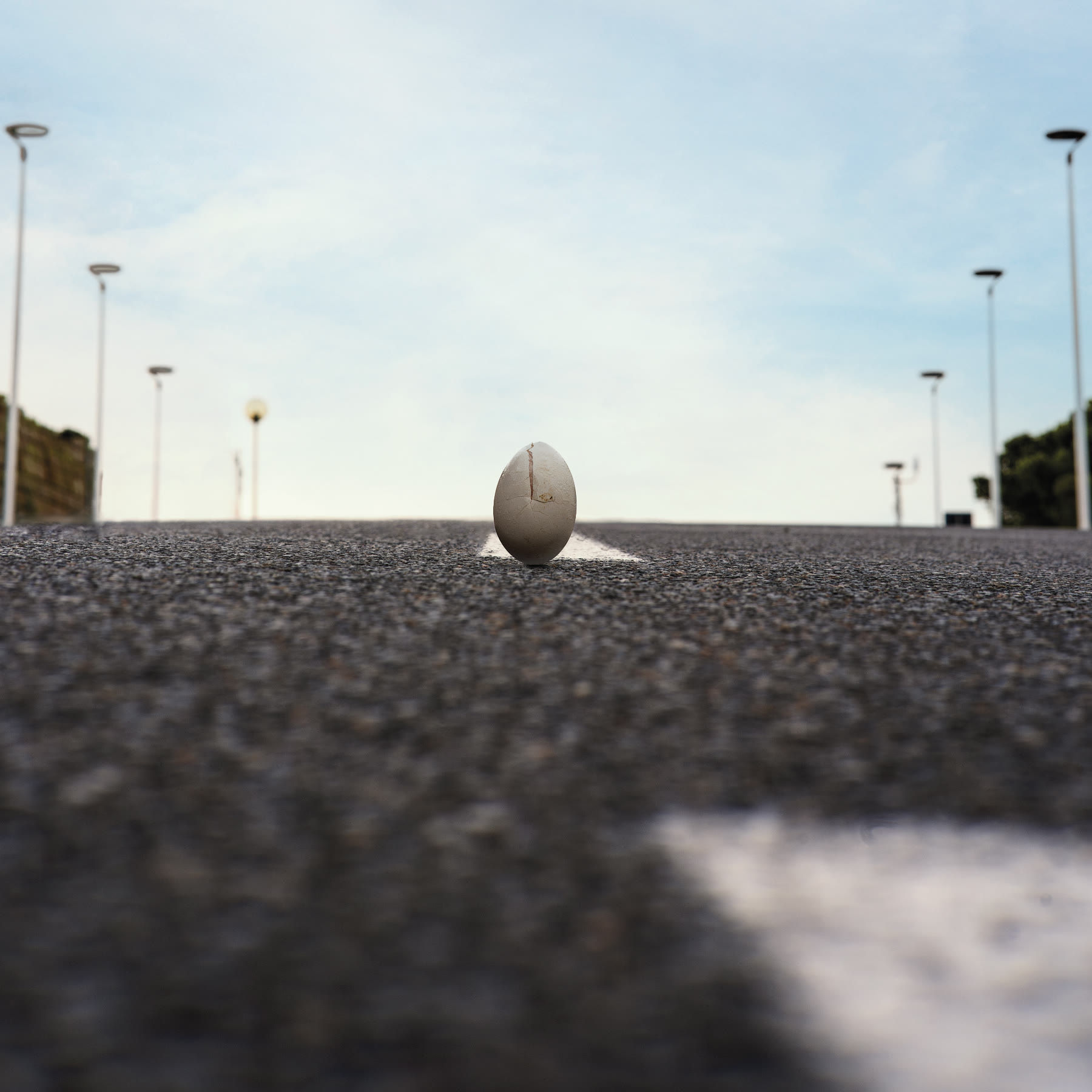 A cracked egg standing upright in the centre of an empty road